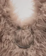 Bolso de mano con diseño triangular y textura de pelo sintético en color beige. Cuenta con un detalle de aro metálico circular en la parte frontal y asa integrada para llevar al hombro.