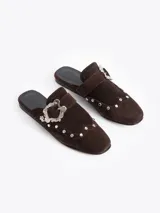 Slide de cuero descarne color marrón, con diseño de punta cerrada, detalle de tachas metálicas y hebilla decorativa en el empeine.