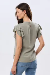 Camisa de lino y viscosa color beige, con cuello mao, escote en V y botones frontales de madera. Presenta mangas cortas con volados delicados.