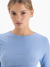 Remera de manga larga en color azul claro, confeccionada en tejido de poliamida y elastano con acabado semitransparente y cuello redondo.