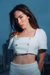 Top corto blanco de tweed con escote cuadrado, mangas cortas abullonadas y cierre frontal con botones dorados.