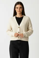 Cardigan de punto acrílico color natural, con cuello en V, botones frontales y corte holgado.
