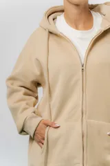 Campera deportiva con capucha de corte oversize, confeccionada en tejido suave con interior forrado en piel sintética. Presenta cierre frontal completo, bolsillos laterales y capucha amplia con cordones largos ajustables.