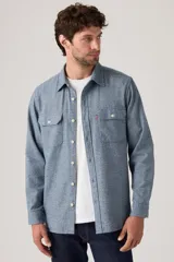 Camisa de estilo worker en color azul marino con textura melange, de manga larga y cuello clásico. Presenta dos bolsillos de parche con solapa en el pecho y cierre frontal con botones.