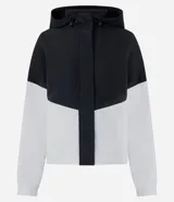 Campera rompeviento deportiva con diseño bicolor en negro y blanco. Presenta capucha con cordón ajustable, cierre frontal y puños elásticos.