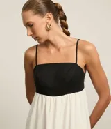Vestido evasé midi de viscolino, con escote recto y breteles finos. Diseño bicolor con busto negro y falda blanca.