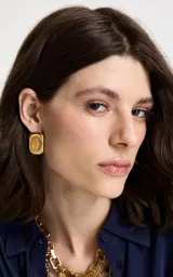 Caravanas de diseño orgánico con estructura de metal chapado en oro y piedra central en tono ámbar.