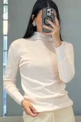 Buzo de tejido de punto fino en color verde, con cuello medio y mangas largas, de corte ajustado al cuerpo.