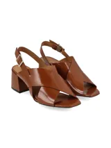 Sandalias de cuero color marrón con acabado brillante, diseño de tiras cruzadas en el empeine, taco cuadrado medio y cierre de hebilla ajustable en el tobillo.