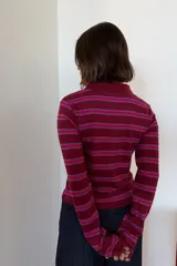 Remera polo de manga larga en tono marrón con rayas horizontales en verde y amarillo mostaza. Cuenta con cuello camisero, escote en V y un pequeño logo bordado en el pecho.
