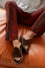 Sandalias bajas de terciopelo marrón con ribete dorado.