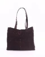 Bolso tipo shopper de gran tamaño, confeccionado en cuero gamuzado color marrón. Presenta estructura rectangular con bordes reforzados en cuero liso oscuro, doble asa de hombro y cierre mediante botón magnético.