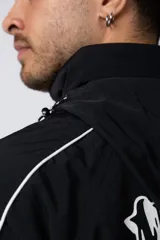 Campera deportiva negra con cierre frontal, capucha ajustable y detalles de líneas blancas en las mangas. Presenta el logo de la marca bordado en el pecho.