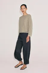 Sweater de punto fino color beige con finas rayas horizontales negras, cuello redondo y manga larga.