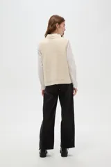 Chaleco de punto texturizado en color marrón chocolate, con cuello redondo y cierre frontal de botones a tono.