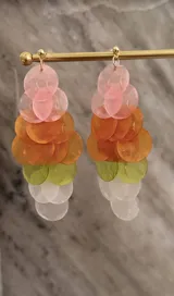 Caravanas colgantes de gran tamaño, compuestas por discos planos de nácar teñido en degradé de colores rosa, naranja, verde y blanco. Cuentan con un perno de plata 925.