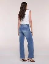 Jean wide leg de tiro medio, color azul claro, confeccionado en denim de algodón con un toque de elastano. Cuenta con cinco bolsillos, presillas para cinturón y cierre frontal con botón. El diseño destaca por su pretina regulable con cruce y broches metálicos.