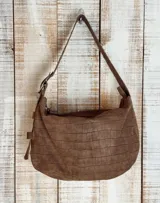 Bolso de hombro tipo hobo con acabado texturizado efecto craquelado en tonos beige y blanco. Cuenta con una correa ajustable con hebilla metálica, cierre superior y diseño espacioso.