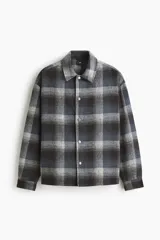 Sobrecamisa de corte relajado en tejido suave con diseño a cuadros. Presenta cuello inglés, cierre frontal con botones a presión, hombros caídos y mangas largas con puños abotonados.