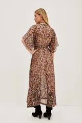 Vestido largo con estampado de hojas en tonos otoñales y metalizados, escote en V con botones frontales y mangas mariposa amplias. Presenta un lazo ajustable a la cintura y abertura frontal en la falda.