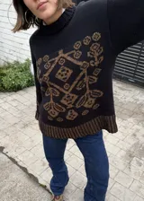 Buzo de punto negro con diseño geométrico y floral en tono marrón, de cuello redondo y manga larga.