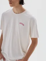 Remera gris oscura de algodón lavado, con cuello redondo, manga corta y corte oversize. Presenta un pequeño logo bordado en el pecho.