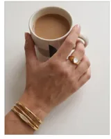 Anillo de acero dorado con diseño de corazón incrustado en nácar blanco.