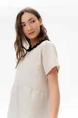 Vestido corto de algodón a rayas horizontales color beige, con cuello redondo negro y falda negra de lino.