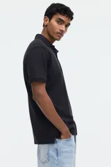 Remera polo de manga corta en piqué de algodón color negro, con cuello clásico y tapeta de dos botones. Corte estándar para una silueta clásica y cómoda.