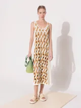 Vestido midi de tejido calado combinado en colores blanco y beige. Diseño sin mangas con breteles anchos, corte recto y aberturas laterales.