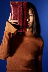 Sobre de cuero negro con solapa, cierre magnético y muñequera con tachas plateadas.