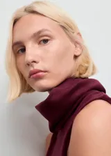 Vestido midi de diseño combinado en color bordó. Presenta un cuerpo sin mangas con cuello alto tipo embudo y una falda acampanada de corte recto.