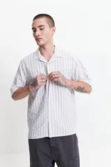 Camisa de manga corta a rayas verticales blancas y grises, con cuello camisero y corte recto. El modelo usa talle M.