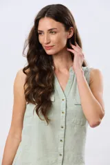 Musculosa de lino color beige, con cuello mao y escote en V, cierre frontal con botones y dos bolsillos plaqué con solapa en el pecho.