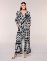 Enterito de calce relajado con caída fluida, escote en V cruzado estilo wrap, mangas tres cuartos estilo kimono y pantalón wide leg. Cuenta con cinto textil a tono para anudar en la cintura y bolsillos laterales, con diseño estampado geométrico en blanco y negro.