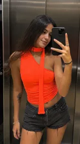 Top de un solo hombro color naranja neón, con diseño ajustado y detalle de tira larga que cae desde el cuello.