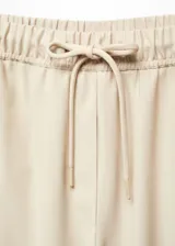 Pantalon de corte jogger confeccionado en tejido fluido, con cintura elástica y lazo ajustable. Presenta diseño largo y dos bolsillos laterales.