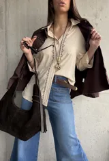 Camisa beige de tejido liviano y calce relajado, con manga larga y detalle de puntilla y bordado en contraste que recorre el frente.