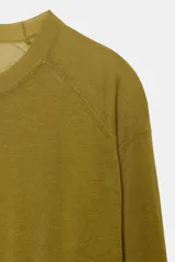 Jersey de punto fino con cuello redondo y manga larga con puños elásticos. Presenta un diseño minimalista con costuras visibles en los hombros.