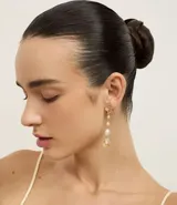 Aros largos dorados con dije de caracol y perlas sintéticas colgantes. Cierre con tornillo.