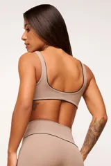 Conjunto deportivo de top y calzas color tostado, confeccionado en poliamida de alta performance con detalles de vivo contrastante. El top cuenta con breteles anchos y diseño slim, mientras que la calza presenta un diseño minimalista de tiro alto.