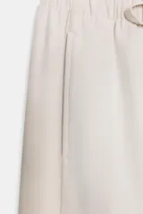 Pantalón de tiro medio color beige, de pierna ancha y corte recto. Cuenta con cintura elástica ajustable con cordones y bolsillos frontales.