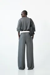 Pantalón de tiro medio color gris oscuro con efecto brillante o tweed, de corte ancho y pierna recta. Presenta doble cintura elástica con cordón de ajuste oscuro y pinzas delanteras marcadas.