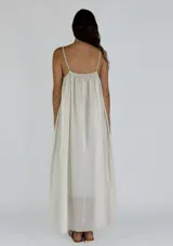 Vestido largo de tirantes finos, con escote en V y detalle de puntilla en el borde. Presenta un diseño holgado y fluido con caída suave.