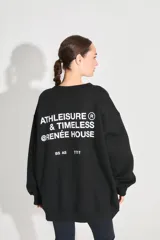 Buzo oversize negro de frisa con cuello redondo, hombros caídos, bolsillos delanteros y estampa serigráfica en delantero y espalda.