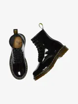 Botas Dr. Martens modelo 1460, de charol negro brillante, con cordones negros, costuras amarillas en la suela y tira trasera con logo AirWair.