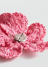 Broche en forma de flor de gran tamaño, confeccionado artesanalmente en tejido de crochet con hilo de poliéster en color rosado.