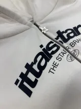 Buzo con cierre frontal completo, capucha amplia y bolsillos tipo canguro. Presenta estampado gráfico en el pecho con la marca IttaiStars y diseño de corte holgado.