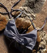 Top de bikini negro con breteles finos que se cruzan en el frente y se atan en la espalda.