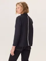 Remera blanca de manga larga con cuello alto, corte holgado y costuras verticales decorativas en el frente.